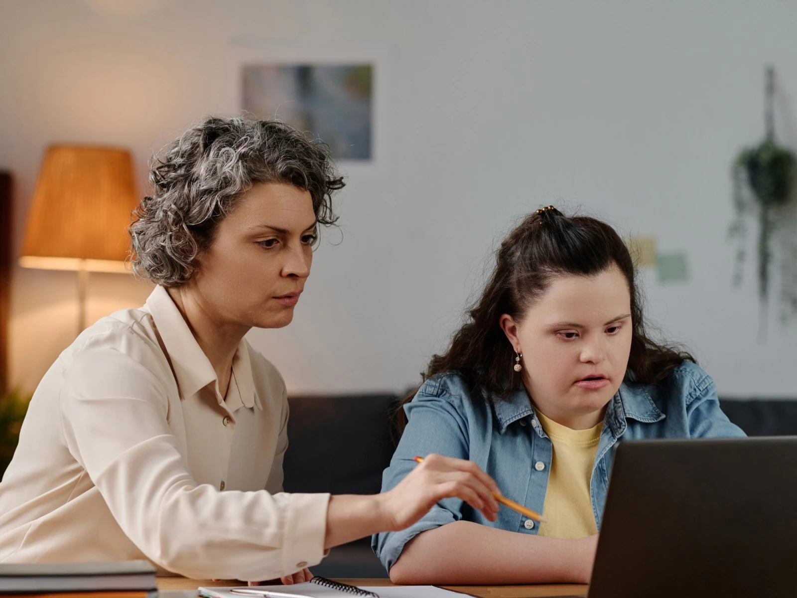 Disabled woman with down syndrome using laptop with support worker